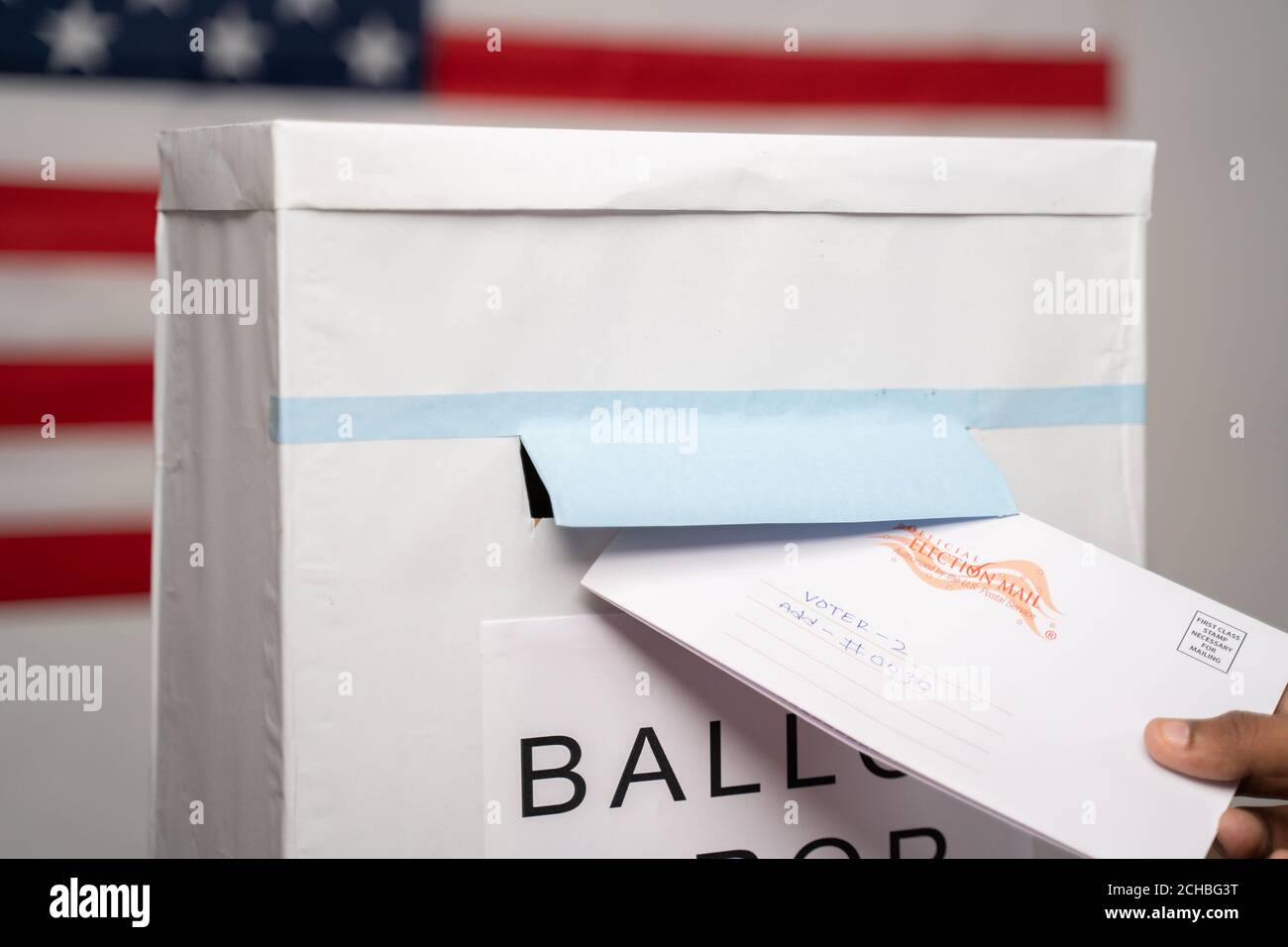 Maski, India 14 September, 2020 : Concept of Mail in vote at US election - Closeup of hands putting Multiple mails inside the ballot box with us flag Stock Photo