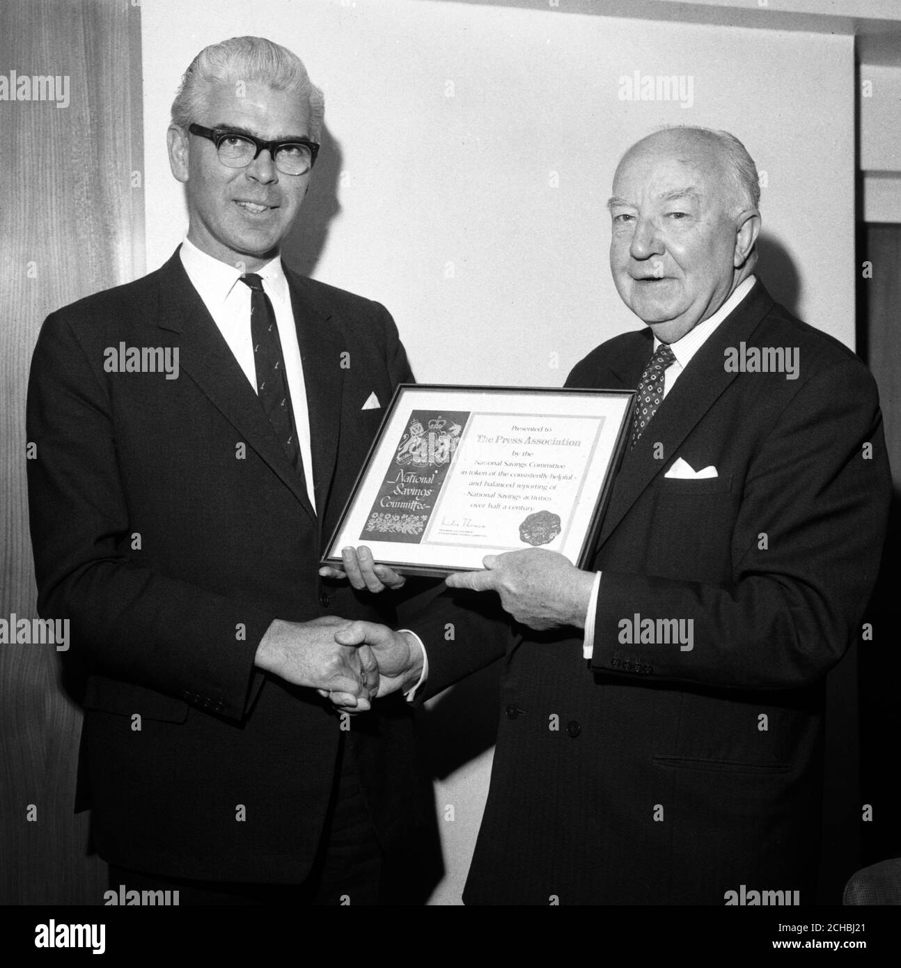 Kenneth A. Searle (l), chairman of the Press Association, receives from Sir Miles Thomas, chairman of the National Savings movement, a special Wedgwood plaque of Queen Elizabeth II's head. The presentation of the plaque, as well as a framed testimonial, was made when Sir Miles was guest of honour at a PA Board luncheon at 85 Fleet Street, London. Stock Photo