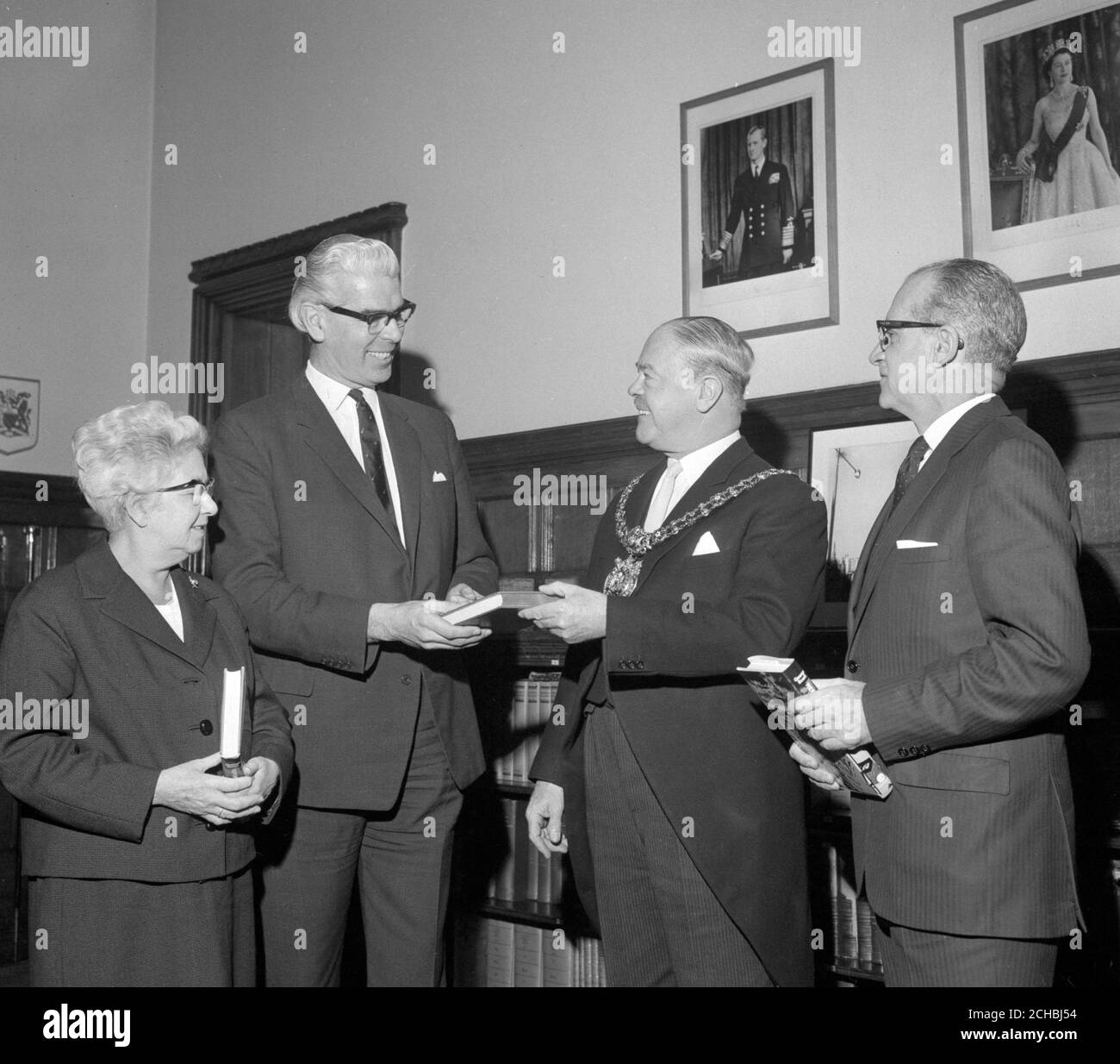 Kenneth A. Searle (l), chairman of the Press Association, presenting a copy of 'Reporter Anonymous: The Story of the Press Association' by George Scott, to Lord Mayor of Manchester, Alderman Harold Stockdale. Also in the image is G. Cromarty Bloom (far right), General Manager of the Press Association, and Deputy Mayor of Manchester, Alderman Elizabeth Yarwood. Stock Photo