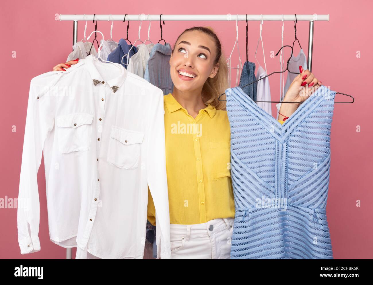 Young woman holding hangers with dress and shirt Stock Photo - Alamy