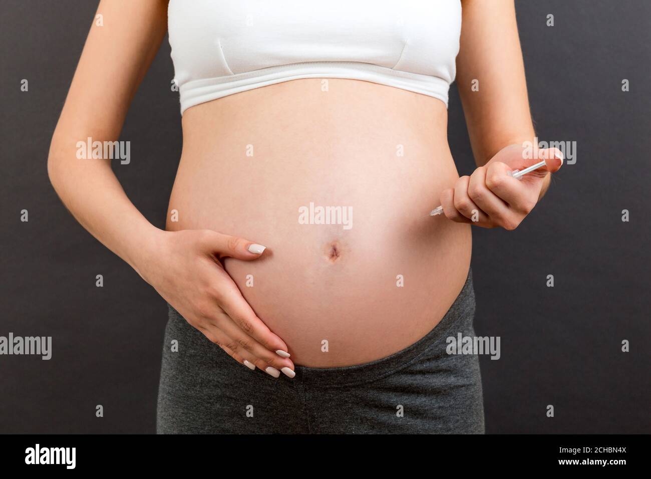 Close up of pregnant woman making injection of insulin in her belly at