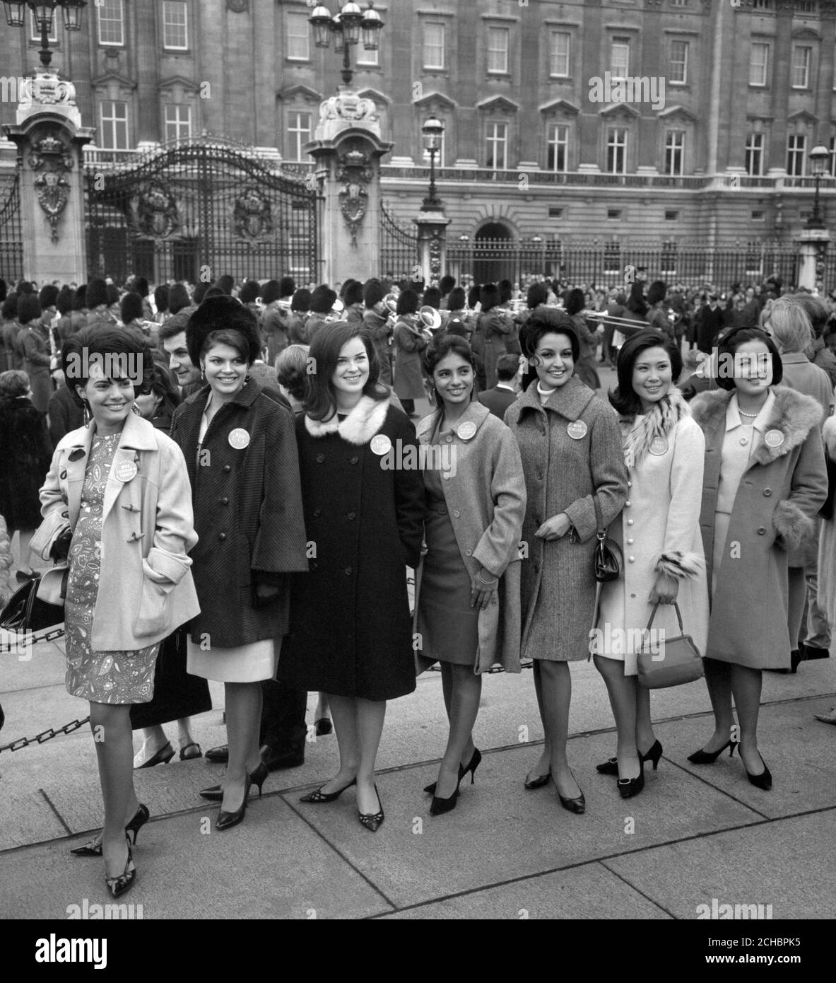 As the new guard marches into Buckingham Palace for the guard-changing ceremony, the Miss World competitors strike a pose while sightseeing in London. (L-R) Diane DeFreitas, 17, (Miss Trinidad and Tobago); Denice Estelle Blair, 19, (Miss USA); Marita Gellman, 23, (Mis Finland); Jeanette Dotel Montes de Oca, 19, (Miss Dominican Republic); Jeannette Kopp Arenas, 19, (Miss Venezuela); Chung Eul-sun, 20, (Miss Korea); and Harumi Kobayashi, 21, (Miss Japan). Stock Photo