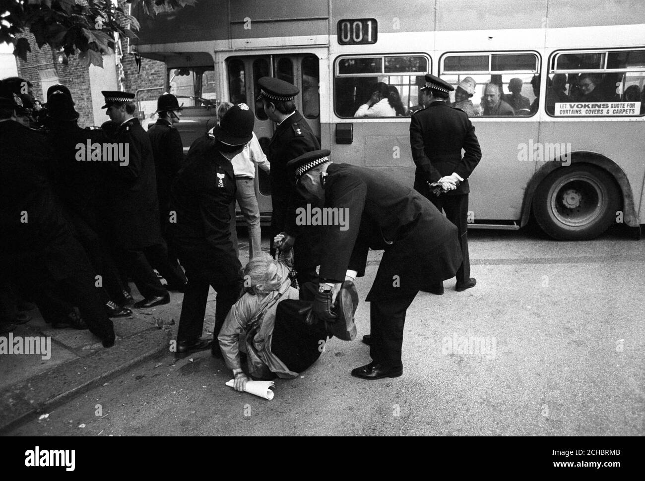 Police removing Mrs Regina Fischer - mother of former world chess champion Bobby Fischer - from the roadway near a bus arriving with the non-unionist workers for the early shift at the Grunwick film processing plant in Willesden, north London. Stock Photo