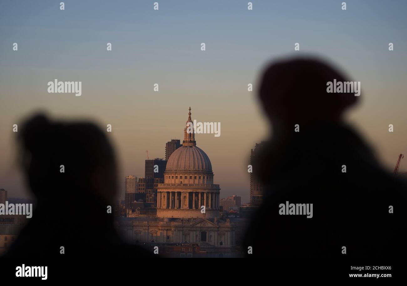 People watch the sun set over St Pauls Cathedral from the Tate Modern in London, as today marks the start of the meteorological winter. Stock Photo