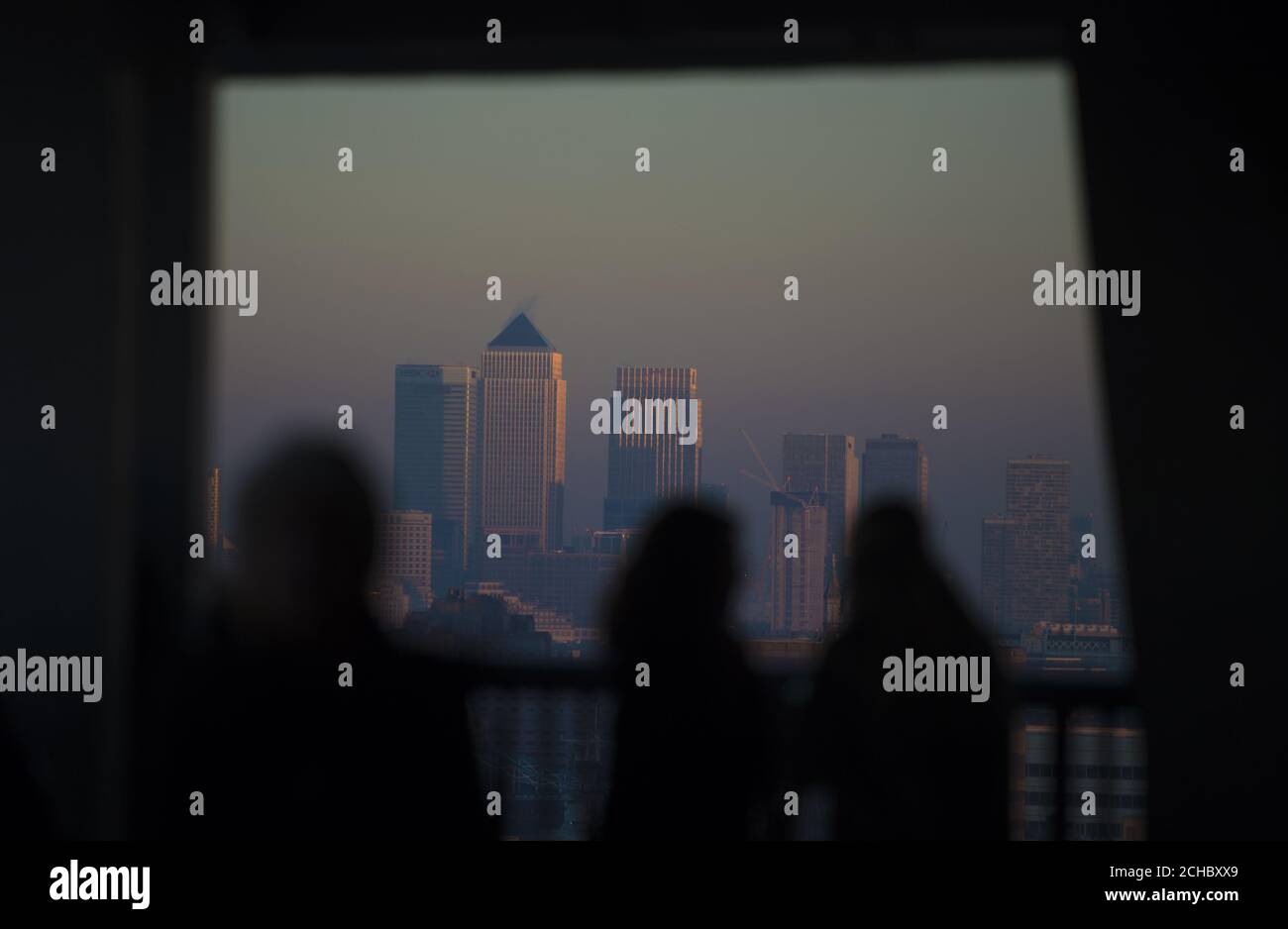 People watch the sun set over Canary Wharf from the Tate Modern in London, as today marks the start of the meteorological winter. Stock Photo