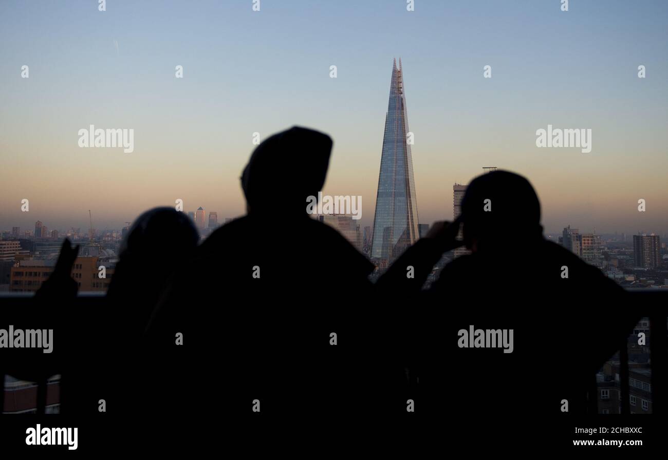 People watch the sun set over the Shard from the Tate Modern in London, as today marks the start of the meteorological winter. Stock Photo