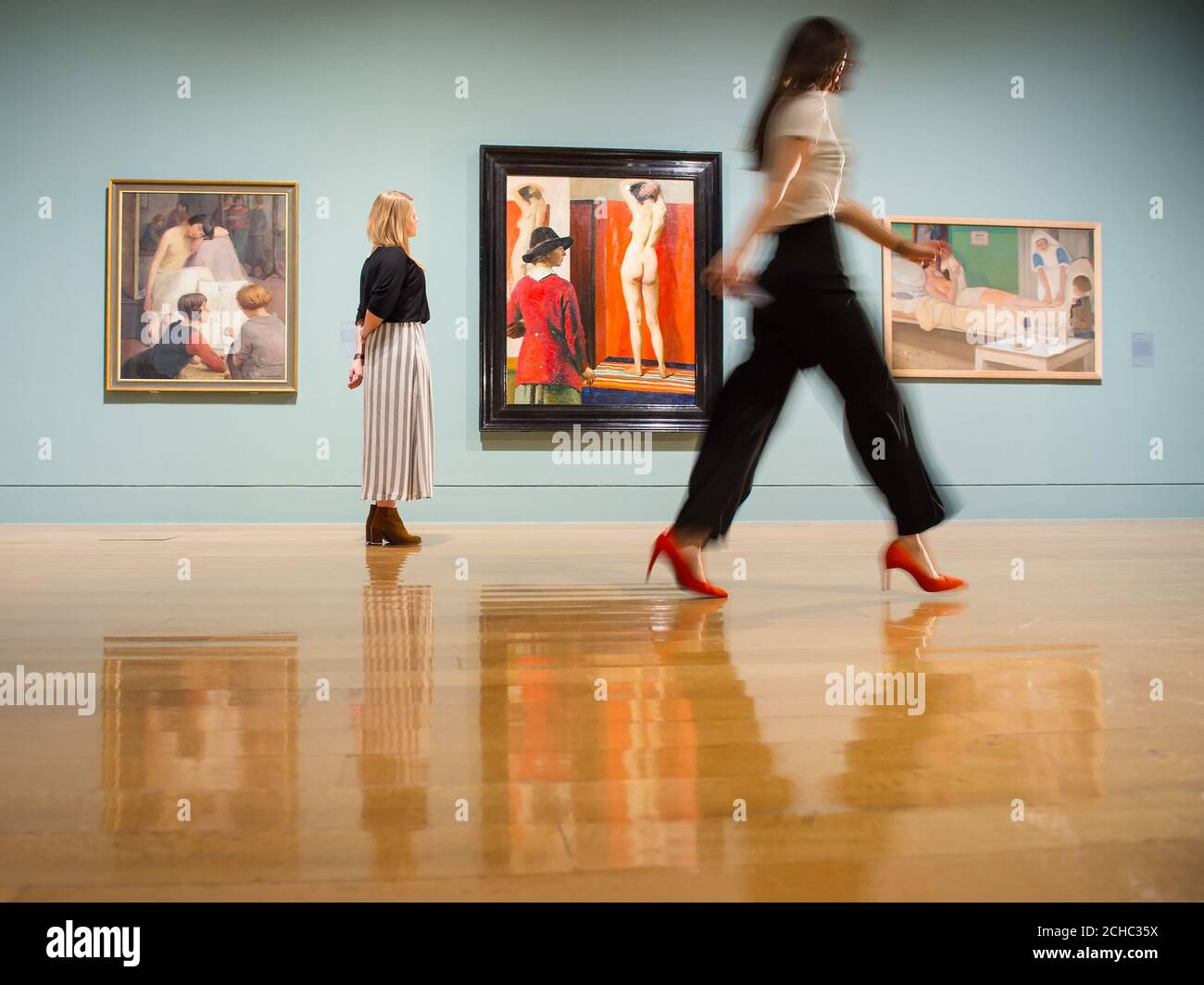 Visitors view (left to right) 'Rest Time in the Life Class' by Dorothy Johnstone, 'Self Portrait' by Laura Knight and 'Romance' by Cecile Walton during a photo call at the Tate Britain in London for their Queer British Art 1861 -1967 exhibition. Stock Photo