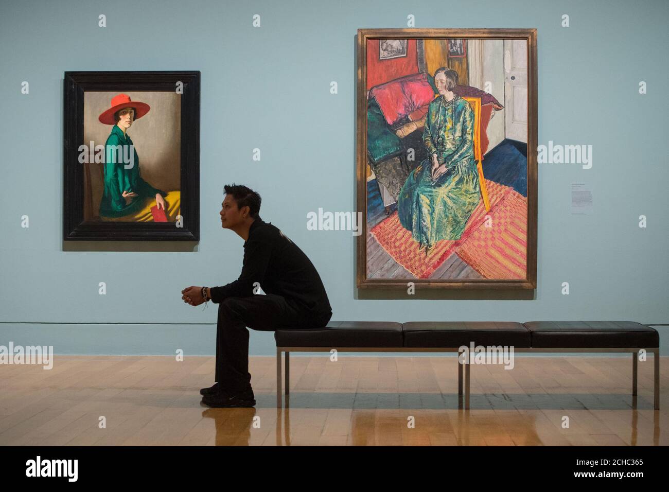 A visitor views 'Lady with a Red Hat' by William Strang, (left) and 'Dame Edith Sitwell' by Alvaro Guevara, during a photo call at the Tate Britain in London for their Queer British Art 1861 -1967 exhibition. Stock Photo