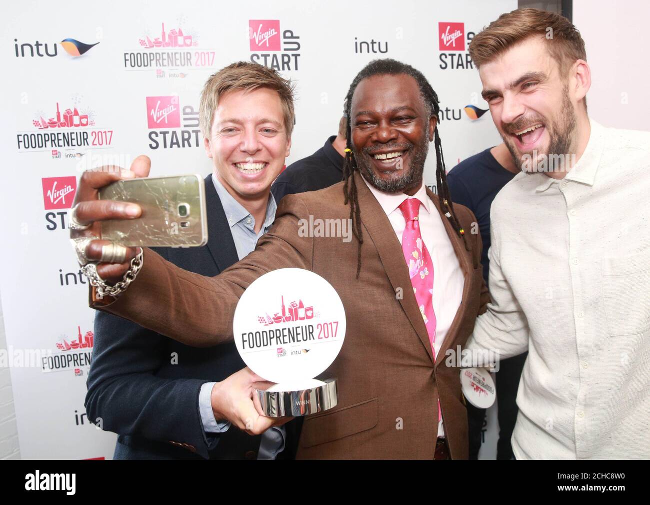 EDITORIAL USE ONLY Judge Levi Roots, founder of Reggae Reggae Sauce (centre) with Nick Coleman and Andy Allen, from Snaffling Pig, who have been announced as the winner of the intu and Virgin StartUp's Foodpreneur competition at Virgin Startup HQ in London, walking away with six week's free retail space at intu Lakeside to run their new business.  Stock Photo