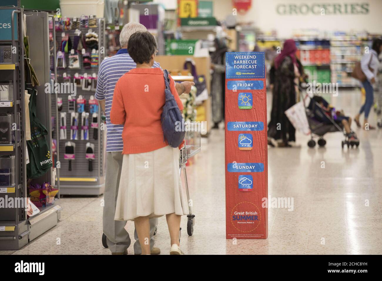 EDITORIAL USE ONLY Customers look at a weatherboard featuring localised weather forecasts, which Morrisons is launching in 491 stores nationwide, to help customers prepare for the unpredictable British weather, at Morrisons in Thornbury, Bradford. Stock Photo