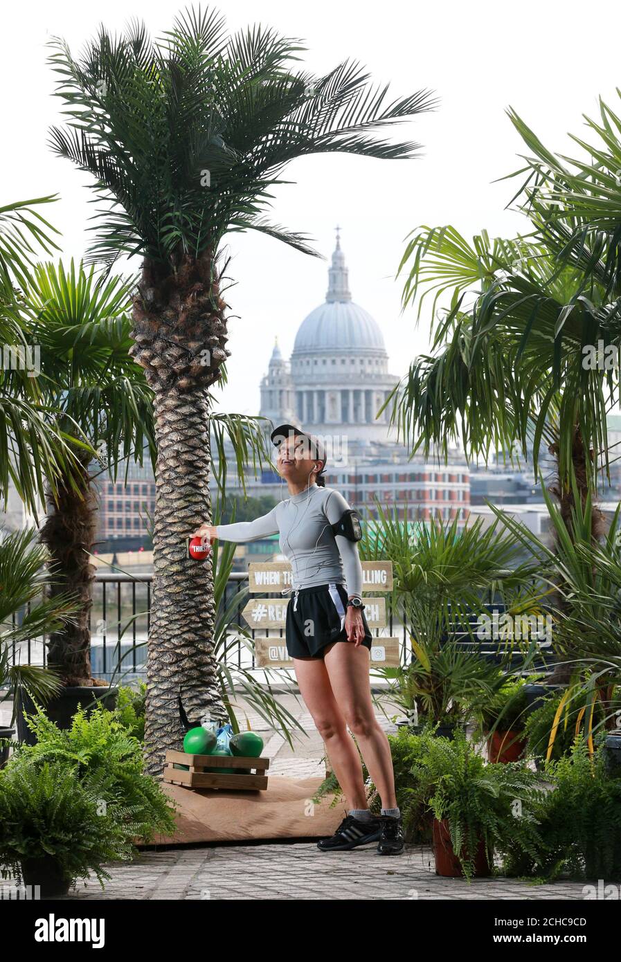 EDITORIAL USE ONLY Chitprapa Boonloi from London picks up a free bottle of coconut water from a pop-up palm tree forest on London&Otilde;s Southbank created by Vita Coco as a tropical retreat for commuters in the midst of this weeks dreary weather.  Stock Photo