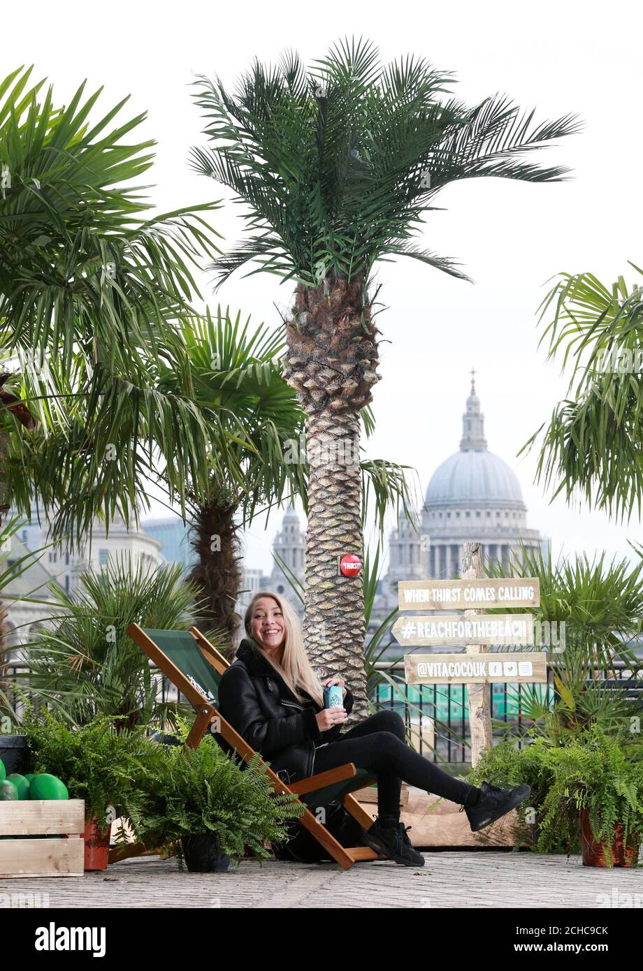 EDITORIAL USE ONLY Mica Whitby from Norwich picks up a free bottle of coconut water from a pop-up palm tree forest on London&Otilde;s Southbank created by Vita Coco as a tropical retreat for commuters in the midst of this weeks dreary weather.  Stock Photo