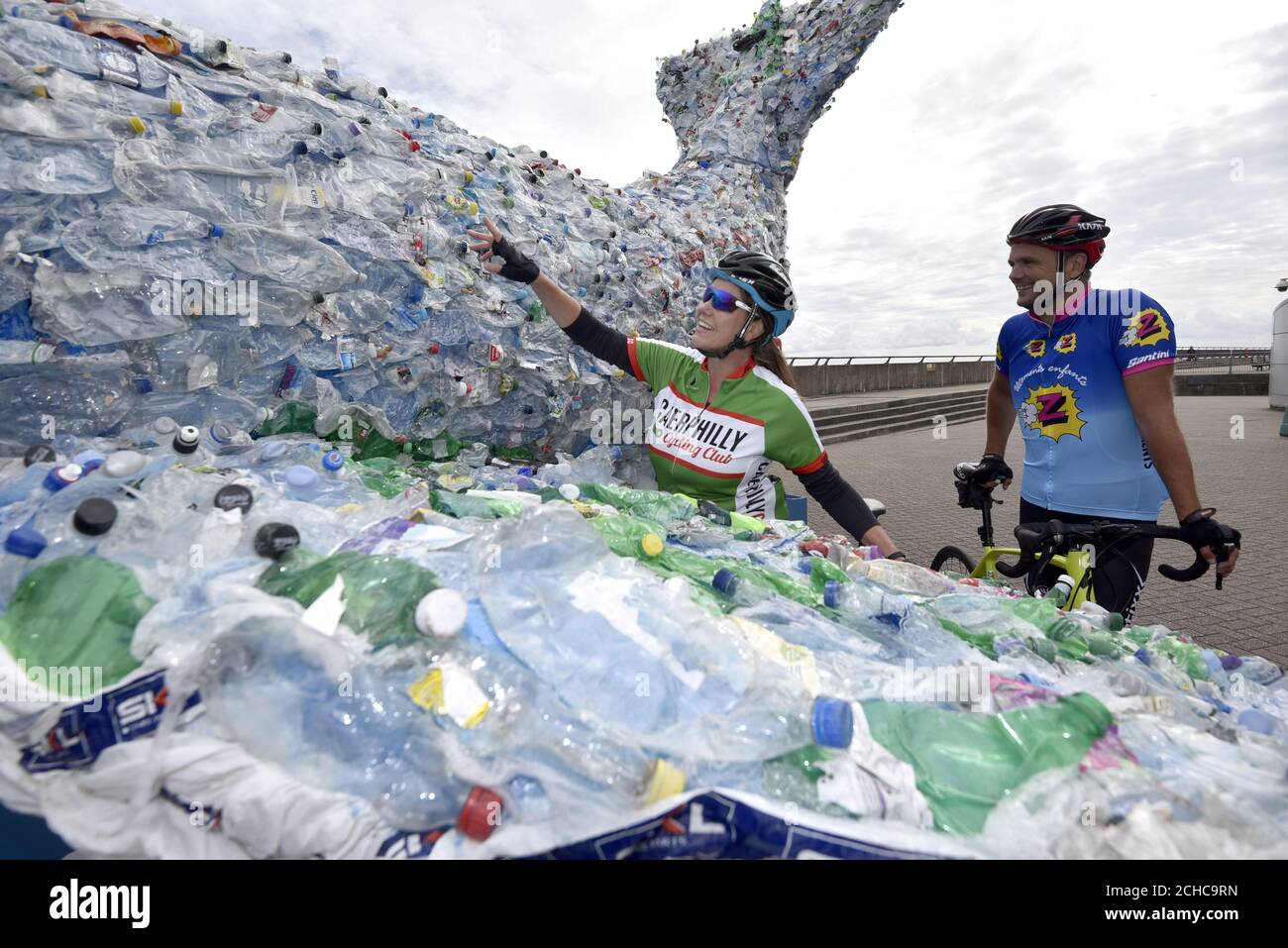 EDITORIAL USE ONLY Local Cyclists look at a Sky Ocean Rescue 10-metre long whale in Cardiff Bay, Wales, which is made entirely from recycled plastic recovered from the ocean, beach cleans and local reCycling plants to raise awareness of the issue of ocean health. Stock Photo