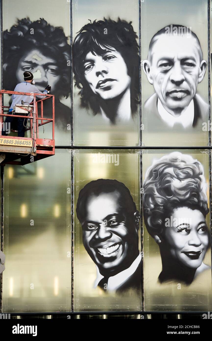 Bristol artist 'Voyder' works on a mural portrait of (left to right) Jimi Hendrix, Mick Jagger, Sergei Rachmaninoff, Louis Armstrong and Ella Fitzgerald, on the front of Colston Hall, Bristol, celebrating artists who have played at the music venue on its 150th anniversary. Stock Photo