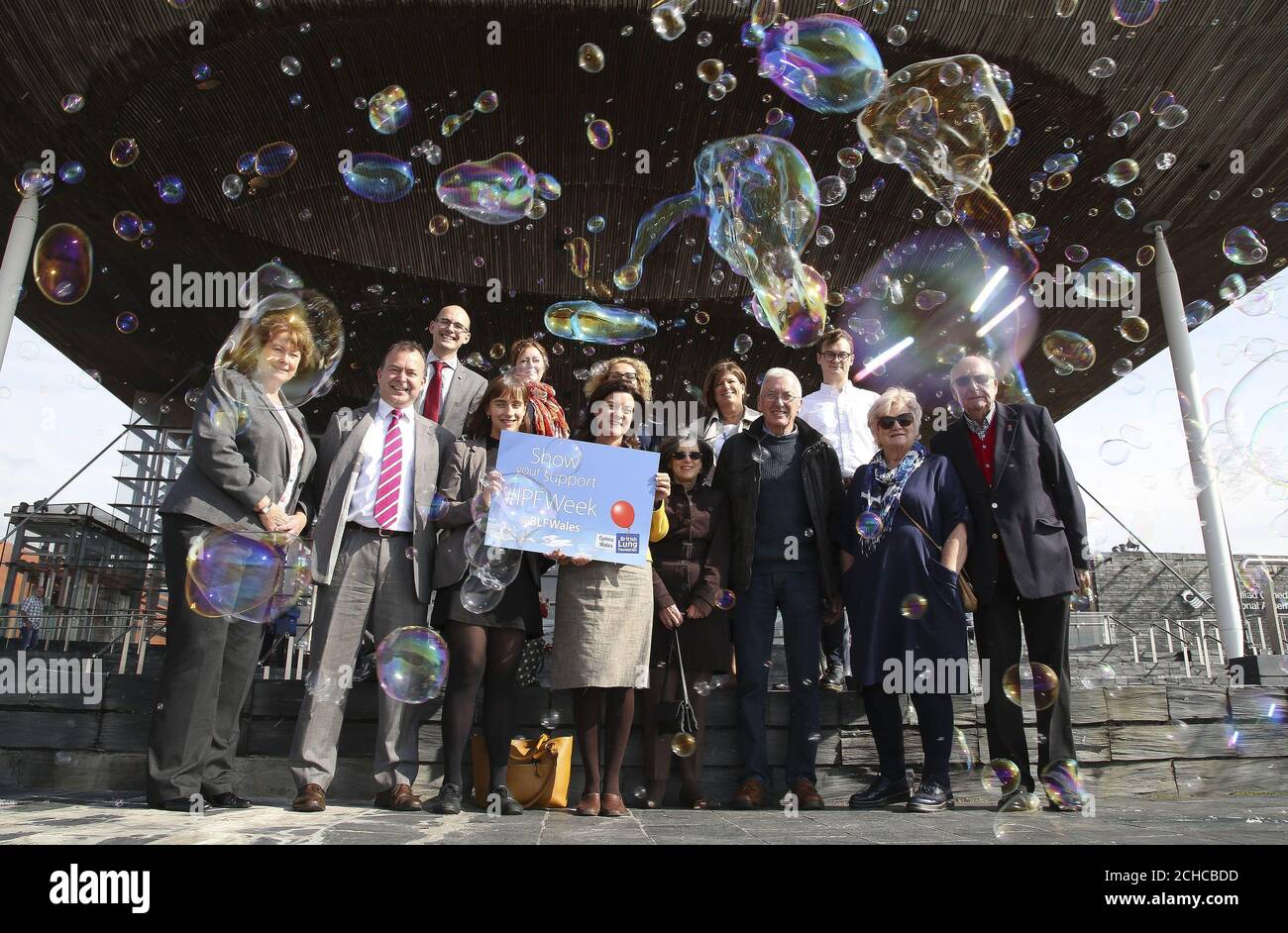Welsh Assembly members, healthcare professionals and IPF patients stand amongst a flurry of bubbles to highlight a lung condition called Idiopathic Pulmonary Fibroses (IPF), at the Senedd in Cardiff. PRESS ASSOCIATION. Picture date: Wednesday September 20 2017. The British Lung Foundation has launched a 'Map for better care' which suggest ways to improve treatments and support for patients with IPF. The disease is characterised by scarring in the lungs with small bubbles that have a 'honeycomb' look and audio recorded on stethoscopes from people's chest that record a bubbli Stock Photo