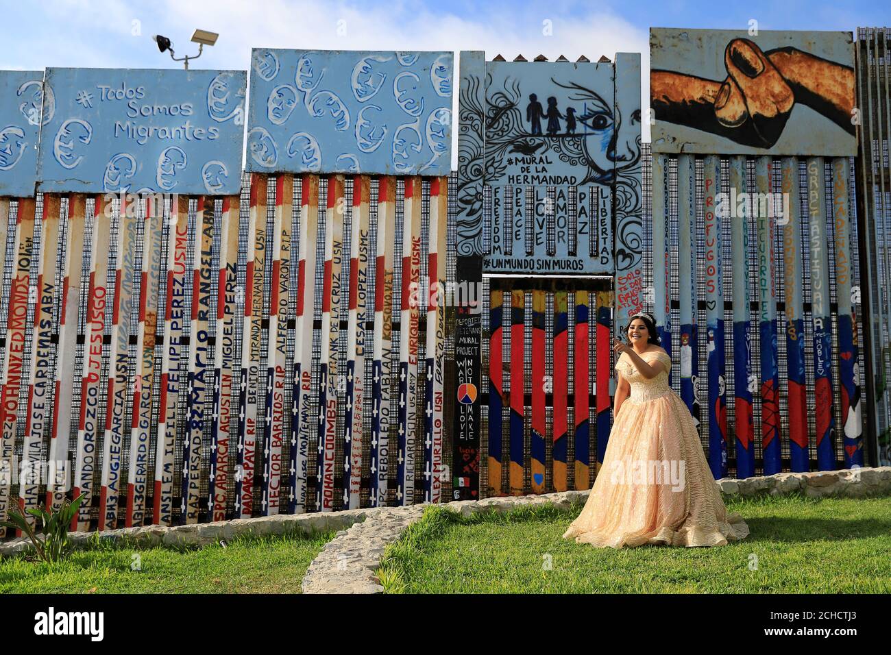 A girl poses in her quinceanera dress near the border fence ...