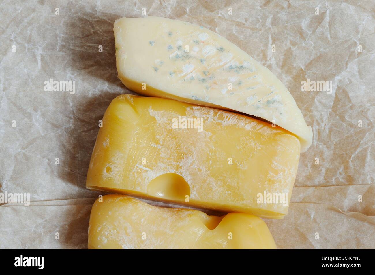 Mold on cheese. Hard cheese with white and black mold on it. Moldy fungus on food.  Fluffy spores mold . Stock Photo