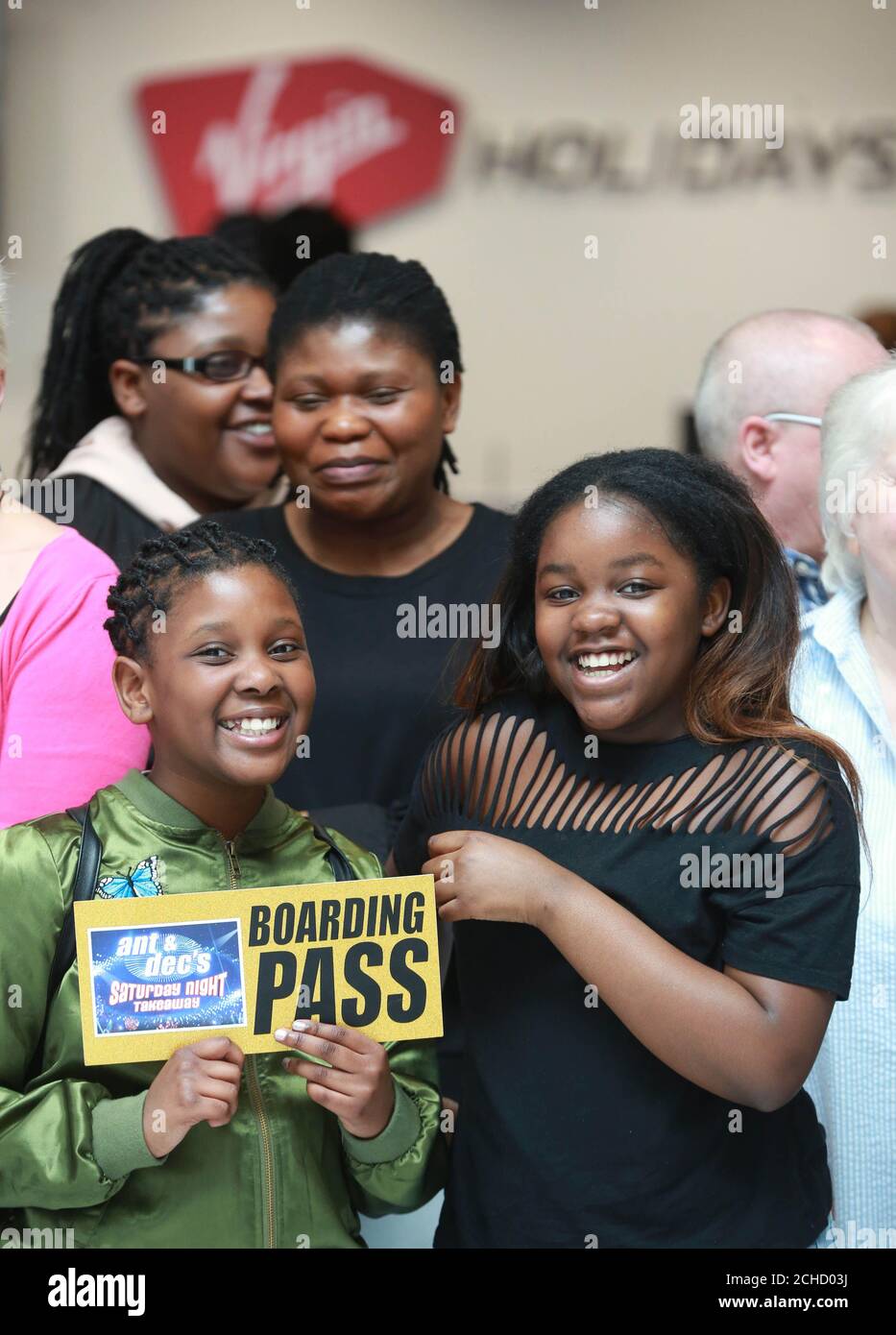 Eva Bandama, aged 9 (left) and Janice Jinks, aged 12, from Luton, join passengers celebrating before boarding a Virgin Holidays airplane, courtesy of ITV's Saturday Night Takeaway, departing for Universal Orlando Resort in Florida, at Gatwick Airport in West Sussex. Stock Photo