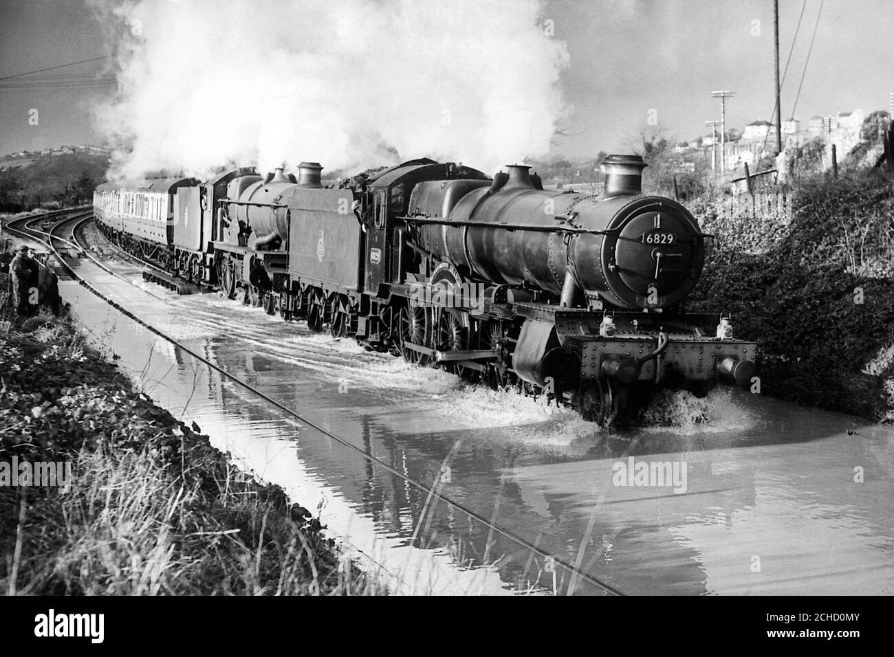 The Cornish Riviera express, headed by two engines, ploughs at walking pace through flood waters at Plympton Devon on its way to London. Stock Photo