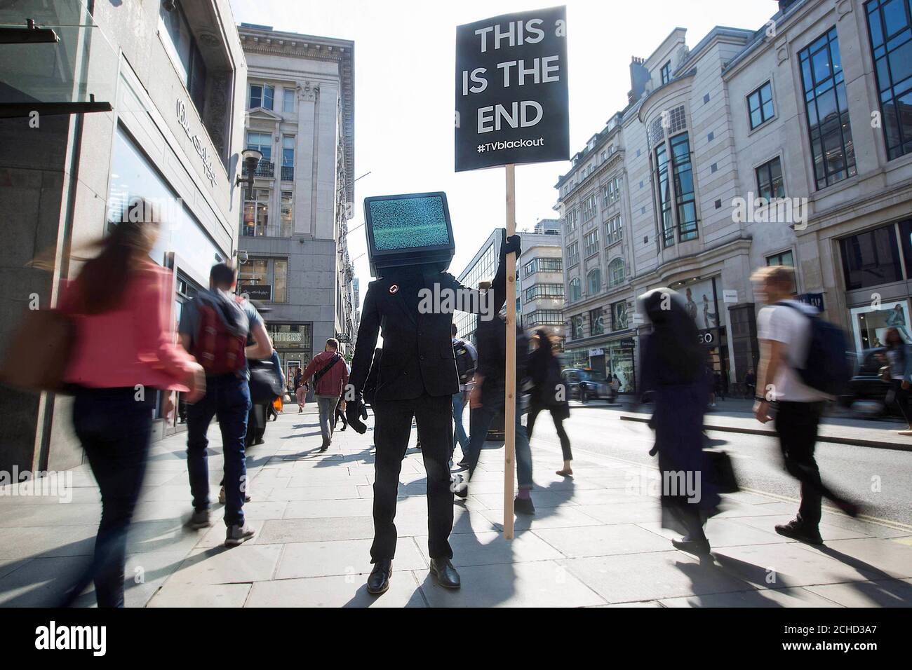 A person with a TV head holds a 'This is the End' protest sign in Oxford Circus, London, as part of a campaign by Samsung to launch their new QLED TV range. Stock Photo