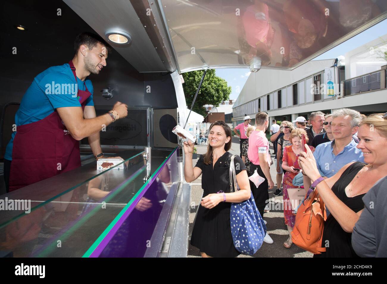EDITORIAL USE ONLY Grigor Dimitrov hands out his limited edition  HŠagen-Dazs Cookies and Cream ice cream to tennis fans on the first day of  The Queen's Club Championship in London Stock Photo -