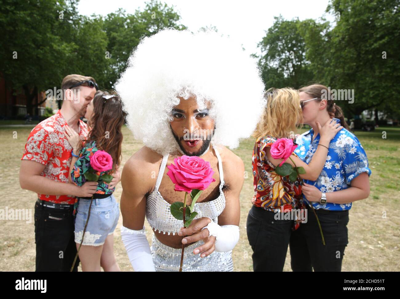 Mercutio, played by Michael Duke, from the upcoming Secret Cinema presents William Shakespeare's Romeo + Juliet, is joined by couples representing the Hawaiian shirt clad Montagues and Capulets to celebrate National Kissing Day and announce an additional 15,000 tickets going on sale, in London. Stock Photo