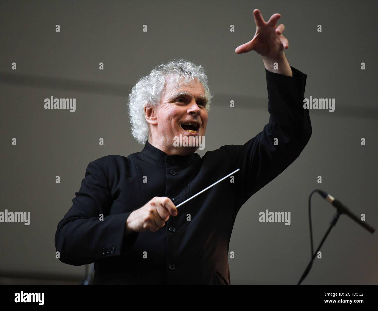 Sir Simon Rattle conducts the London Symphony Orchestra as they perform Stockhausen's Gruppen for three Orchestras in Tate Modern's Turbine Hall, London. Stock Photo