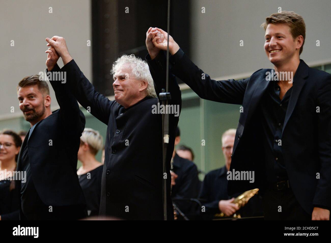 (left to right) Matthias Pintscher, Sir Simon Rattle and Duncan Ward after they conducted the London Symphony Orchestra perform Stockhausen's Gruppen for three Orchestras in Tate Modern's Turbine Hall, London. Stock Photo