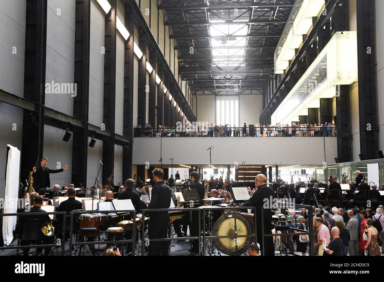 Sir Simon Rattle, Matthias Pintscher and Duncan Ward conduct the London Symphony Orchestra as they perform Stockhausen's Gruppen for three Orchestras in Tate Modern's Turbine Hall, London. Stock Photo