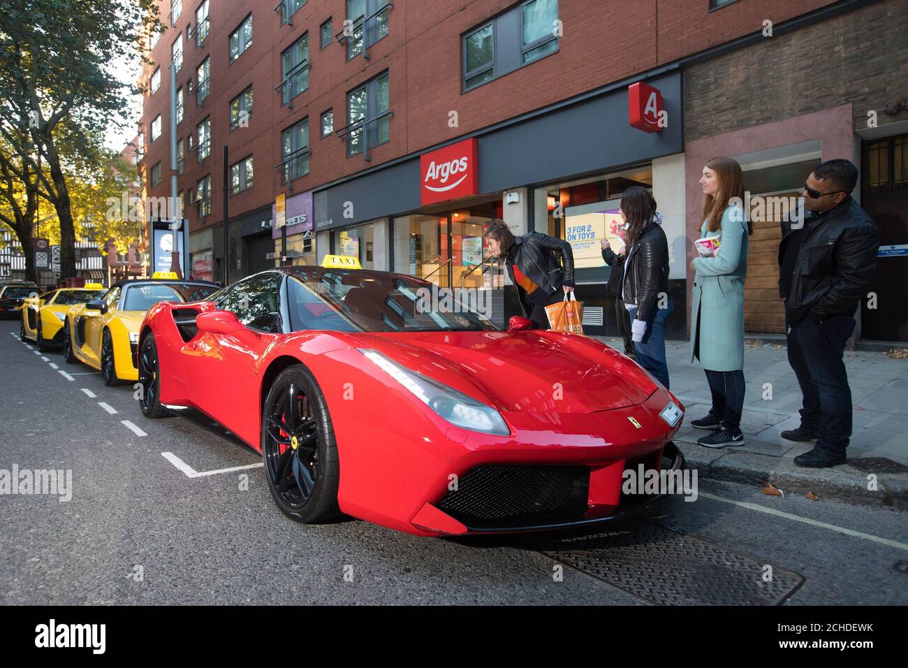A Ferrari 488 Spyder lines up outside Argos, alongside an Audi R8 V10 Plus Spider and a Lamborghini Aventador, waiting to chauffeur home customers who've pre-ordered a copy of the highly-anticipated Forza Horizon 4, which has been launched today by Xbox One. Stock Photo