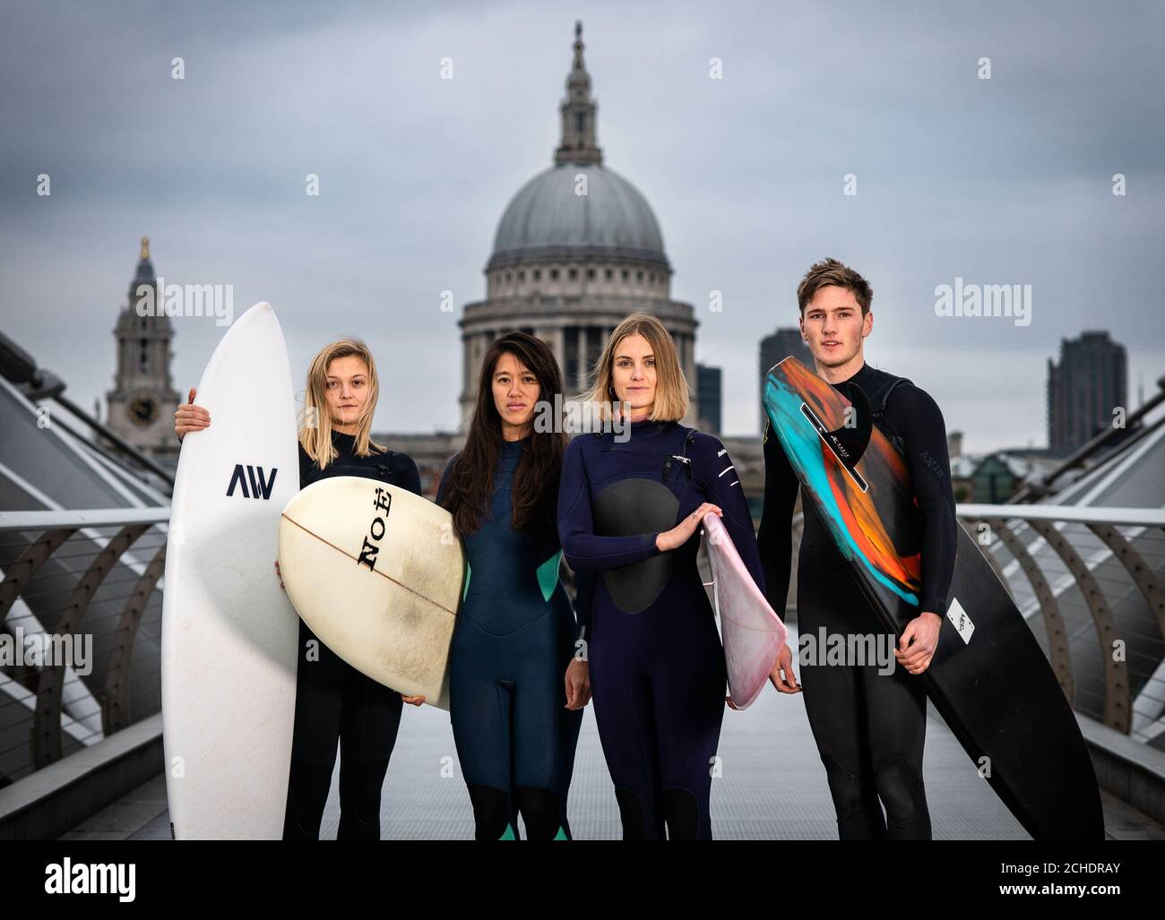 EMBARGOED TO 0001 TUESDAY NOVEMBER 27 EDITORIAL USE ONLY (Left to right) Surfers Jessica Rowe, Veranika Lim, Sophie Hellyer and Frank Hodgson cross London&Otilde;s Millennium Bridge as a partnership is announced between Lee Valley Regional Park Authority and The Wave to create an inland surfing destination in the capital for people of all ages, backgrounds and abilities.  Stock Photo