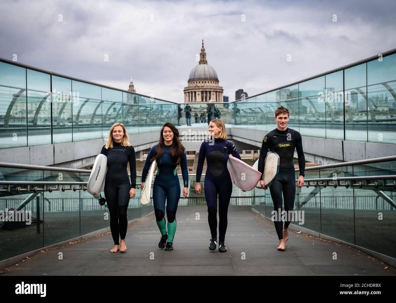 EDITORIAL USE ONLY (Left to right) Surfers Jessica Rowe, Veranika Lim, Sophie Hellyer and Frank Hodgson cross LondonÕs Millennium Bridge as a partnership is announced between Lee Valley Regional Park Authority and The Wave to create an inland surfing destination in the capital for people of all ages, backgrounds and abilities. Stock Photo