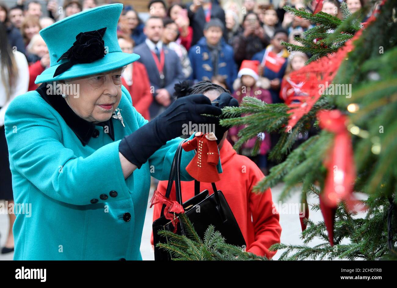 Queen Elizabeth II and Shylah Gordon, aged 8, attach a bauble to a Christmas tree during her visit to Coram, the UK's oldest children's charity, to open the Queen Elizabeth II Centre at its base in central London. Stock Photo