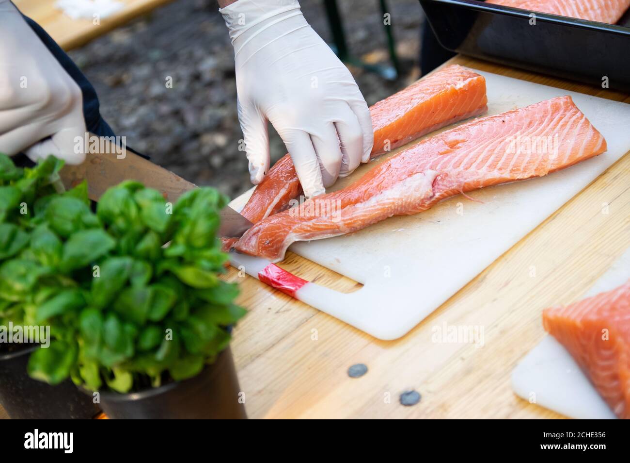 Man hands cutting pink raw salmon with knife on white board Stock Photo