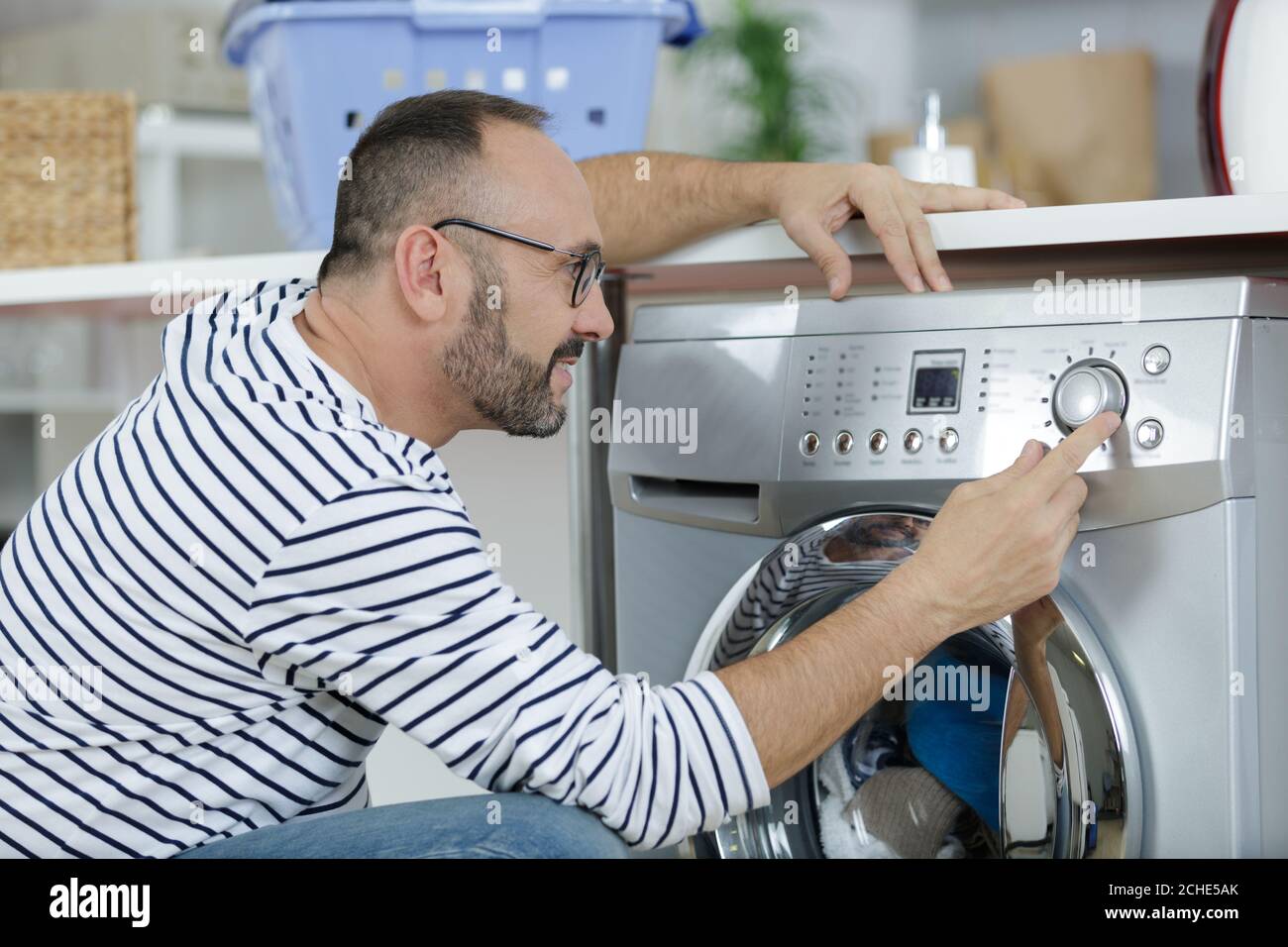 a middle aged man using washing machine Stock Photo