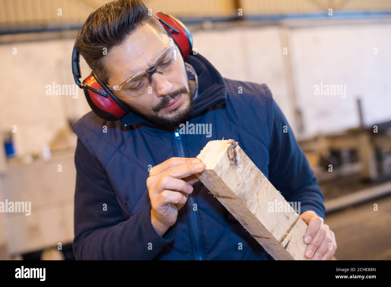carpenter checking wood plank evenness at workshop Stock Photo