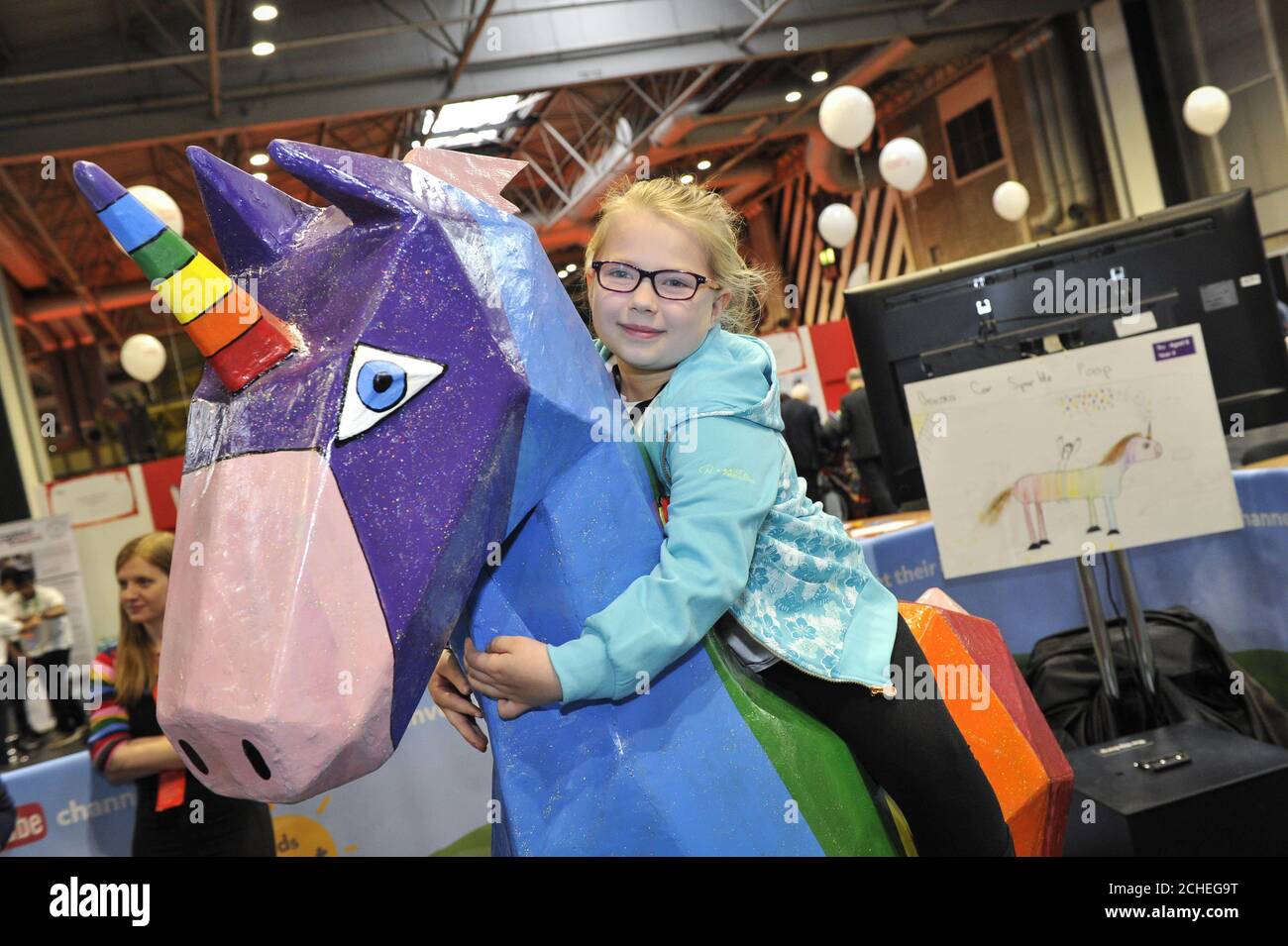 EDITORIAL USE ONLY Tru Stevens, aged 8 from Cornwall, the winner of Kids invent Stuff, sits on her design 'Pooicorn' at The Big Bang Fair at the NEC in Birmingham. Stock Photo