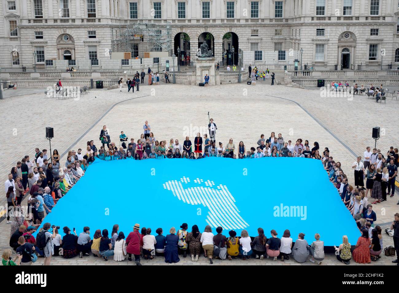 EDITORIAL USE ONLY People hold a giant version of a new human rights flag designed by artist and activist Ai Weiwei to launch a week of activity for Fly The Flag, a project commissioned by a wide-ranging group of arts organisations and human rights charities to mark the 70th anniversary of the Universal Declaration of Human Rights at Somerset House in London.  Stock Photo