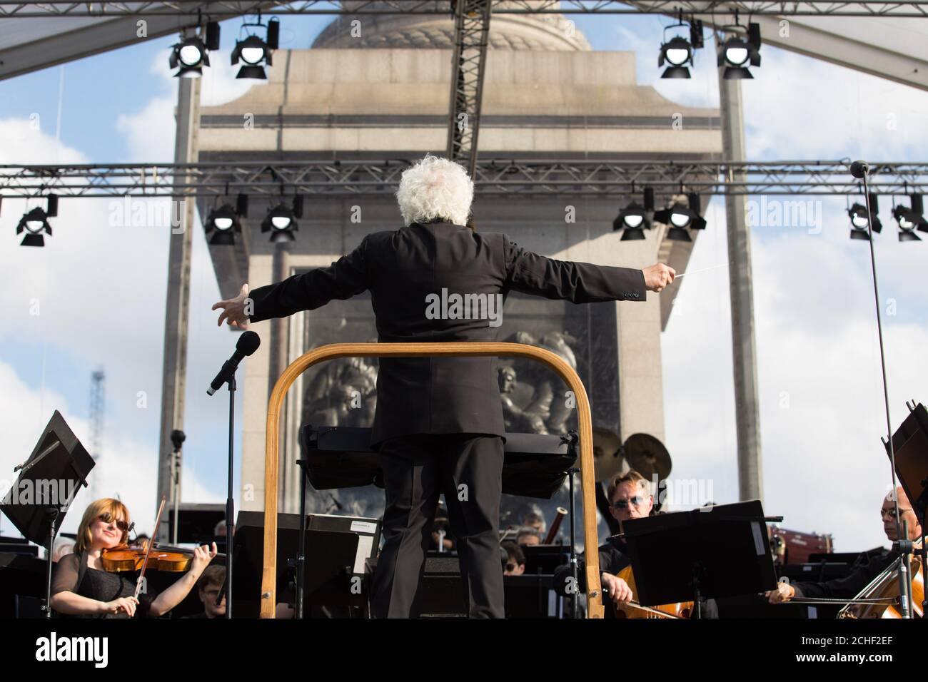 Sir Simon Rattle conducts the London Symphony Orchestra with musicians aged 8 to 18 from the Guildhall School of Music & Drama and young musicians from the LSO On Track programme at the BMW Classic event in Trafalgar Square London. Stock Photo