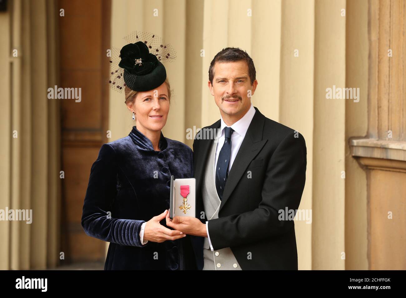 Bear Grylls and his wife Shara holding his OBE during an investiture ceremony at Buckingham Palace, London. Stock Photo