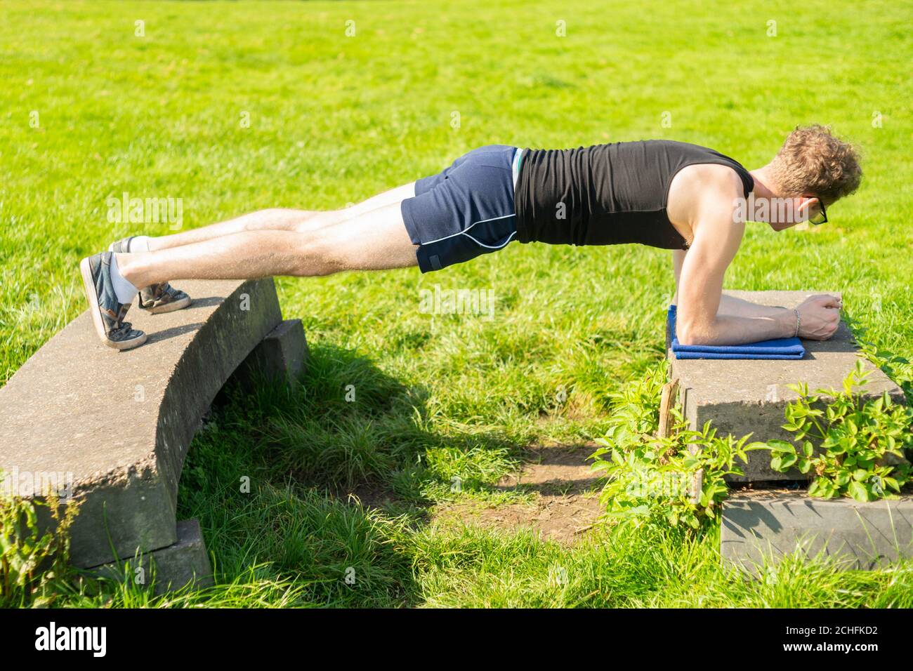 Young man performing plank exercise in an outdoors environment. Strengthen core muscles, exercise, keep fit, health Stock Photo