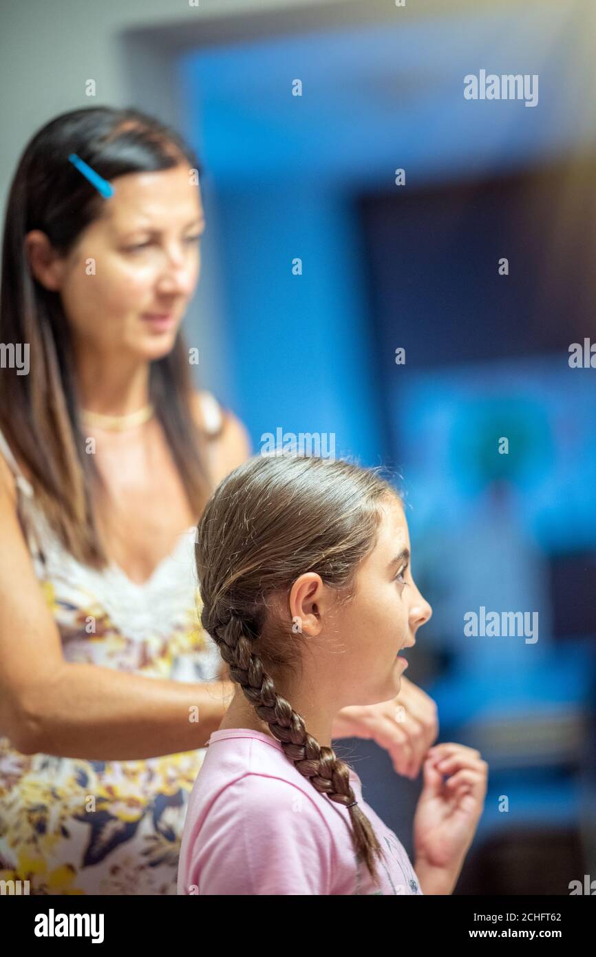 Woman combing her daughter's hair at home before school. Stock Photo