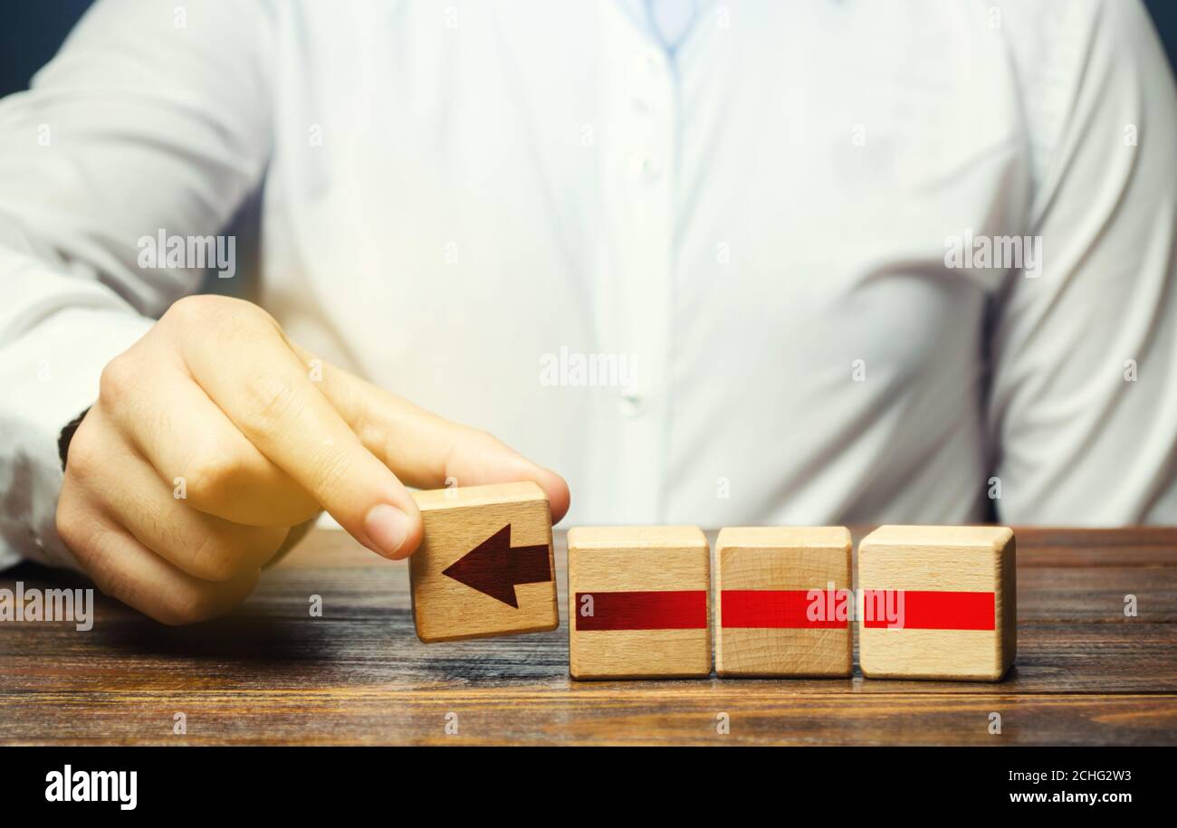 Man builds an red arrow from blocks. Business development, growth process concept. Progress and movement forward. Career promotion, improving skills. Stock Photo