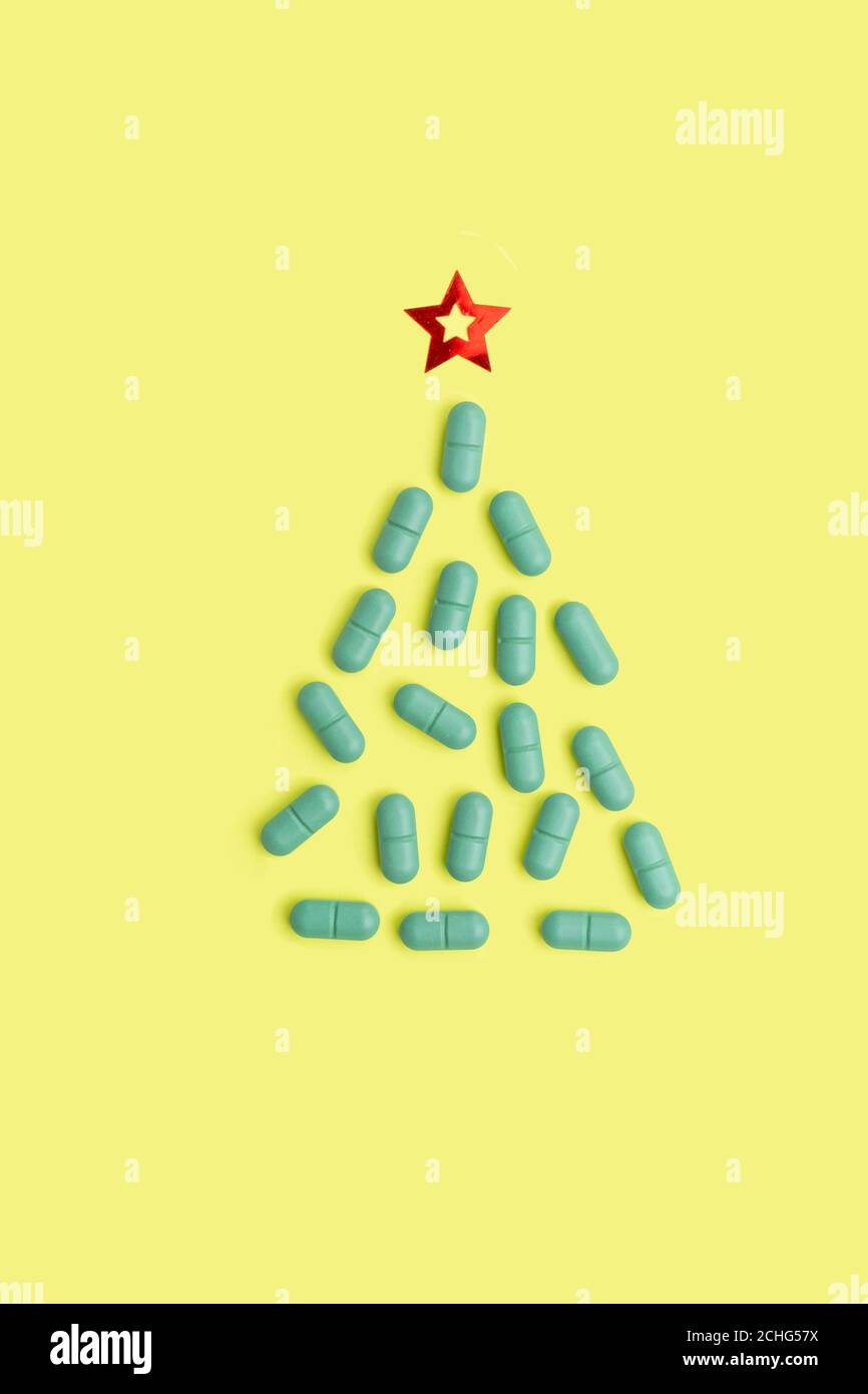 Christmas tree made of pills for Christmas, conceptual yellow background on the New Year theme