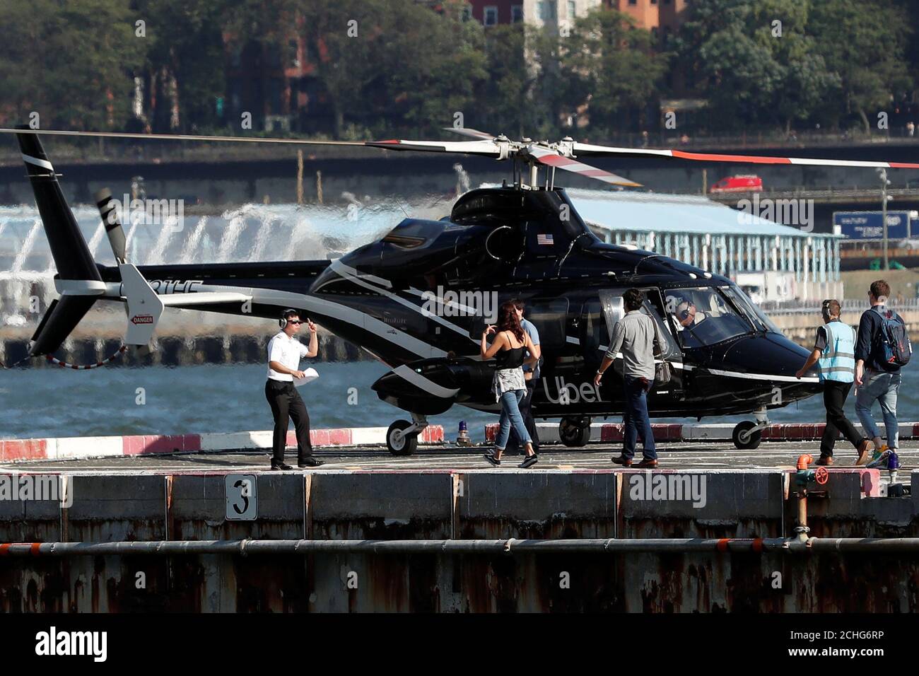 Passengers are escorted to a waiting helicopter operated by Uber 