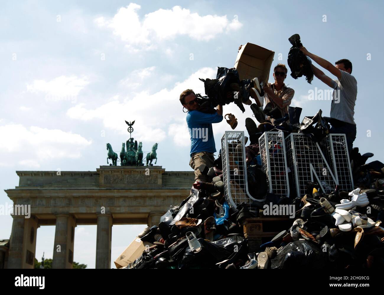People pile up shoes to build the monument 'Pillar of Shame' in front of the Brandenburg Gate in Berlin, July 10, 2010, commemorating the 1995 mass murder of Muslim men and boys in the town of Srebrenica. The Society for Threatened Peoples has collected some16,744 shoes from Bosnia, Austria, Switzerland and Germany to build the monument is to draw attention to the failure of the United Nation (UN) to prevent the killing of 8372 refugees who died during the Bosnian War in an area that was declared a UN safe zone.  REUTERS/Thomas Peter (GERMANY - Tags: POLITICS) Stock Photo