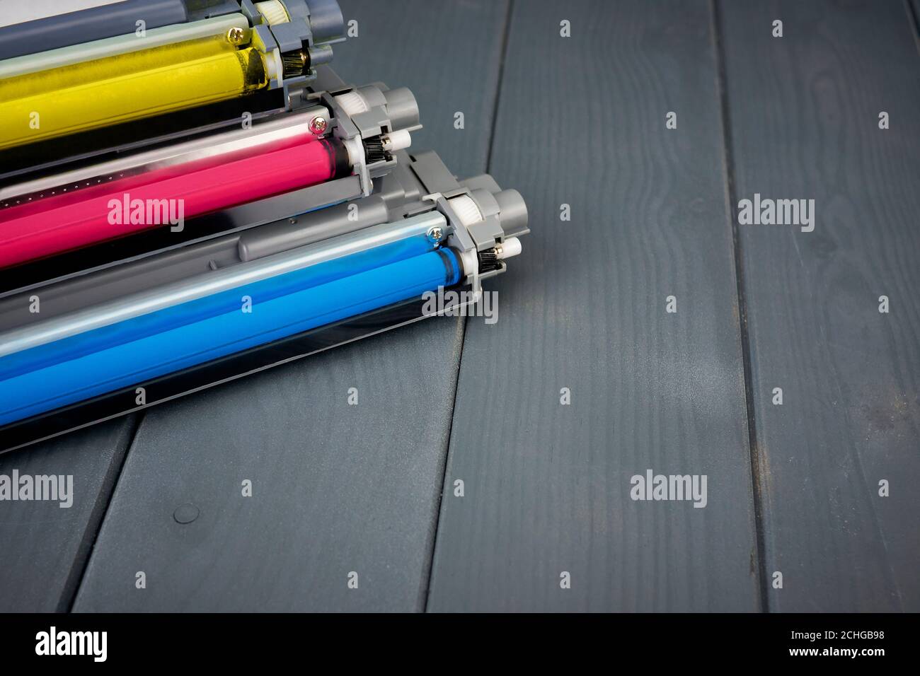 Three used toner cartridges in a color laser printer on gray wooden background for recycling Stock Photo
