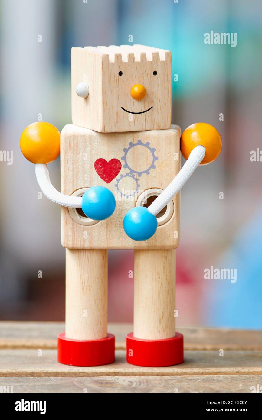 Wooden toy robot with red heart and smile. Defocused background. Stock Photo