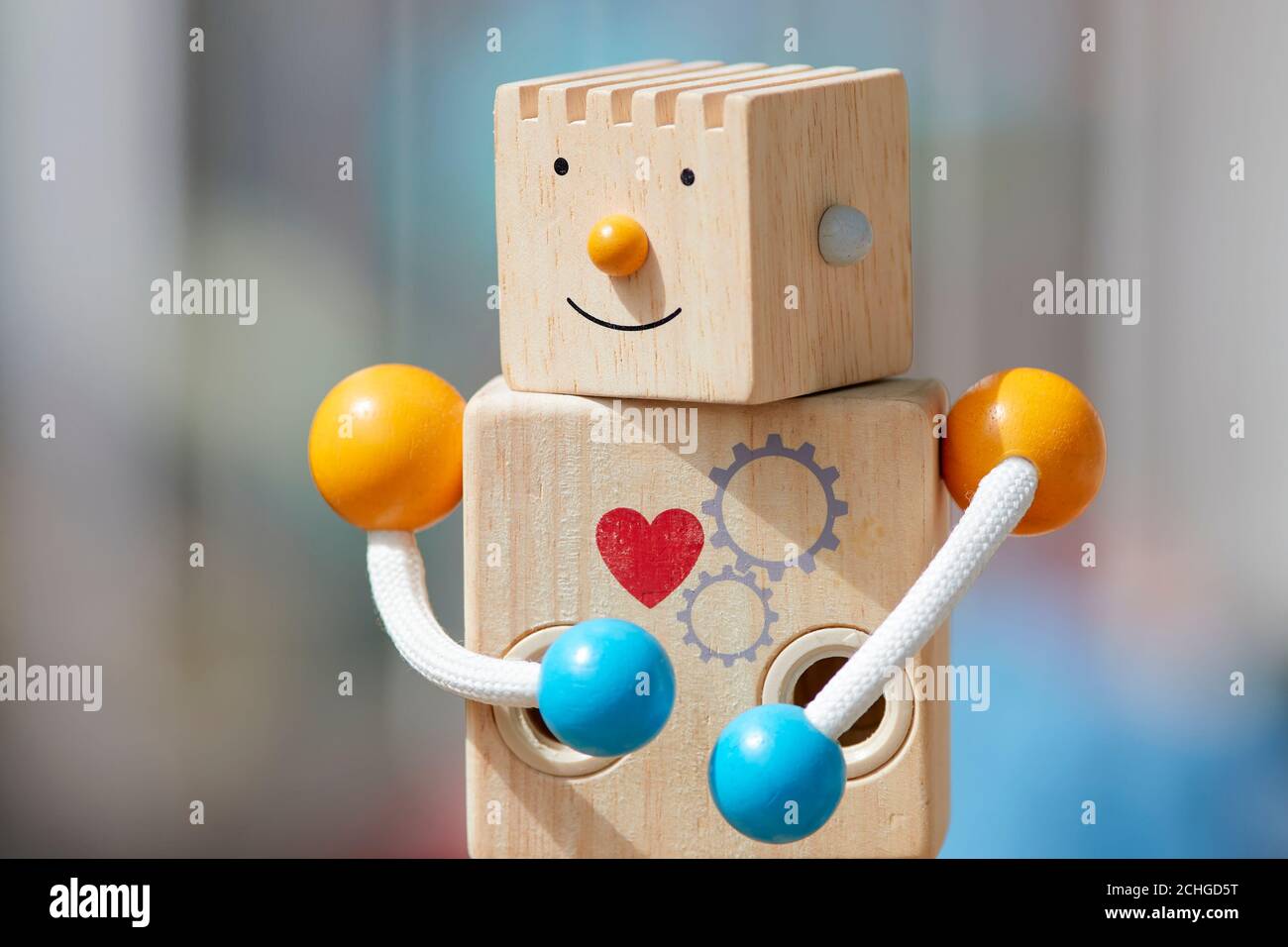 Wooden toy robot with red heart and smile. Defocused background. Stock Photo