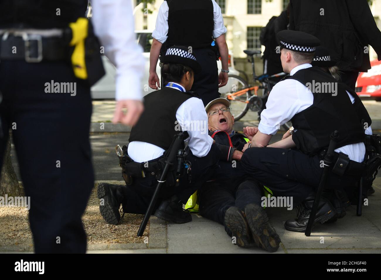 A man is held by police officers during a protest against the Covid-19 lockdown outside New Scotland Yard in London. Stock Photo